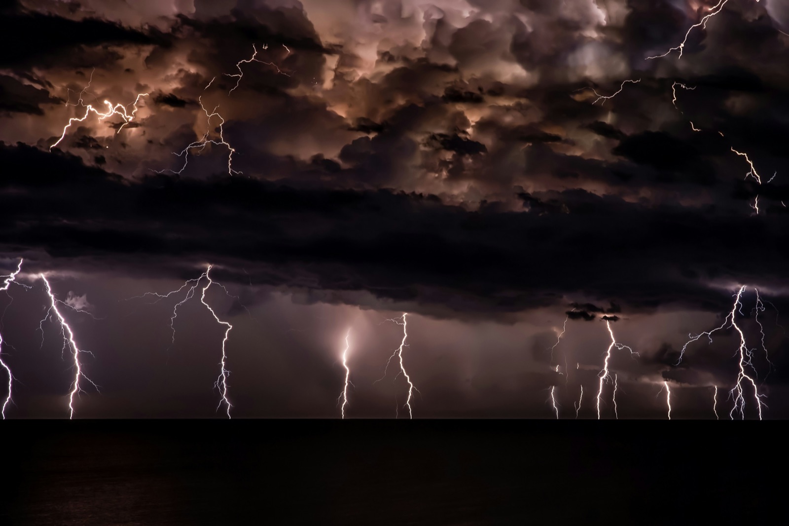 Lightning storm over open water at night
